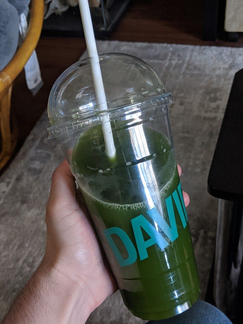 A large plastic cup of green matcha, the text DAVID in aqua coloring spans across it.