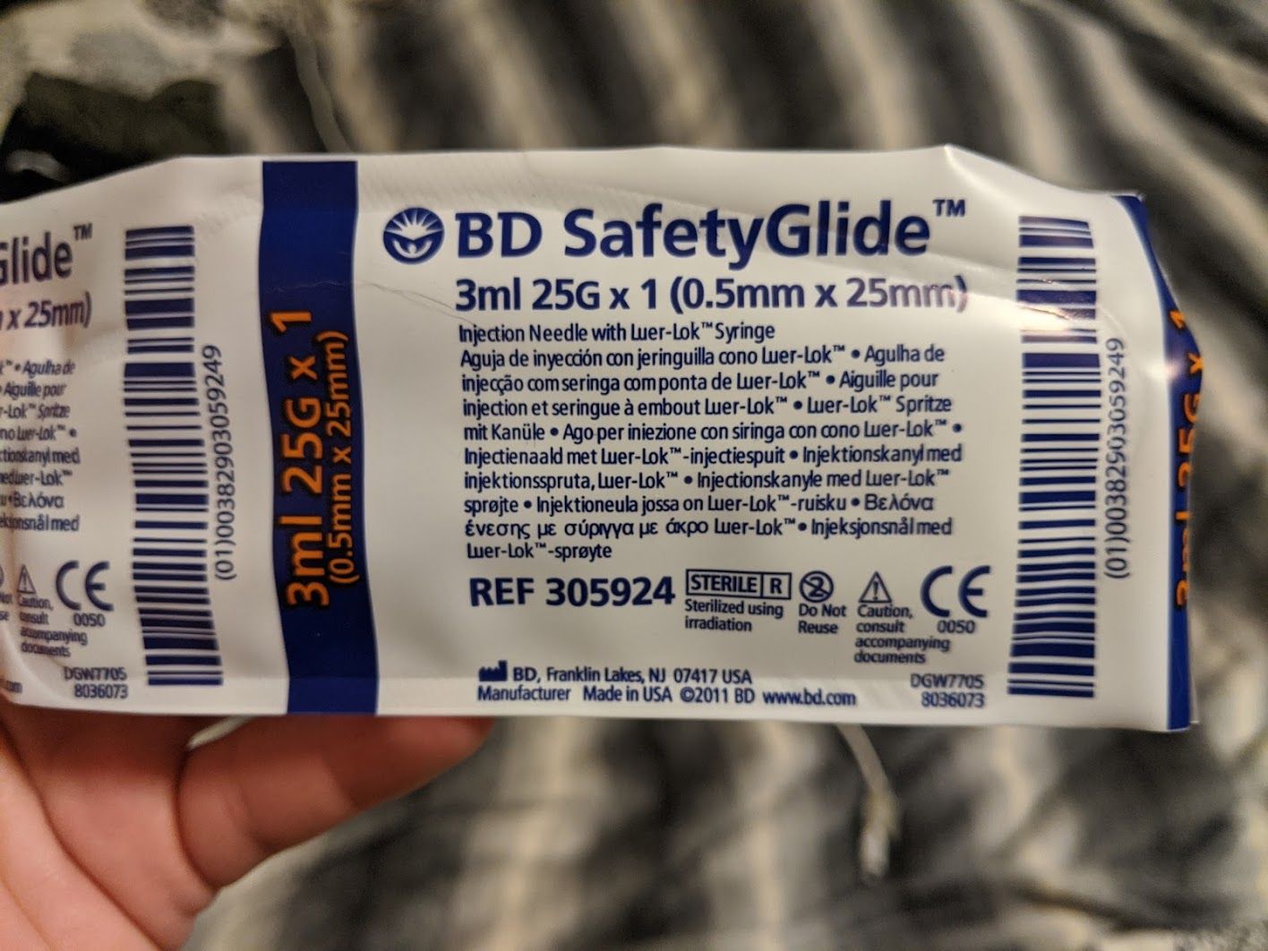 The packaging for a 25gauge needle with some small multi-lingual medical text on it.