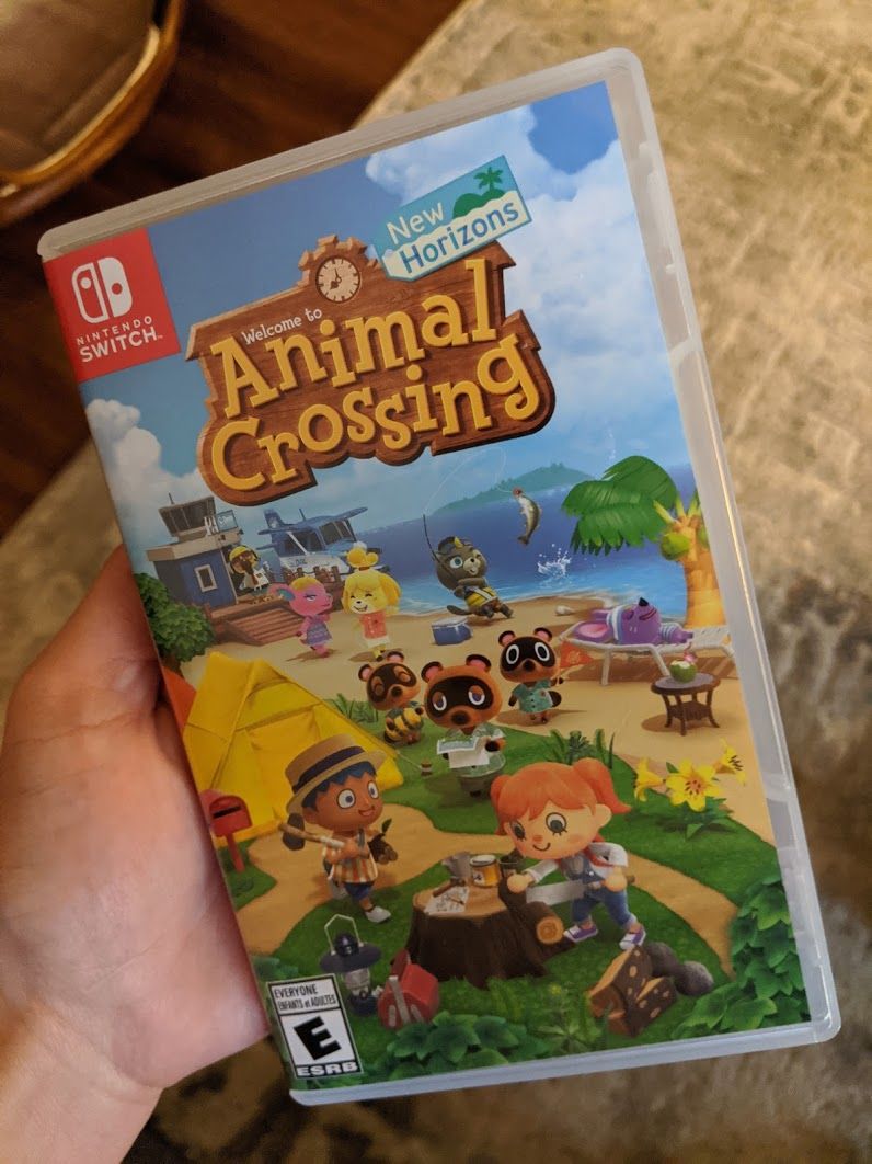 Me holding up a physical copy of Animal Crossing: New Horizons for the Nintendo Switch