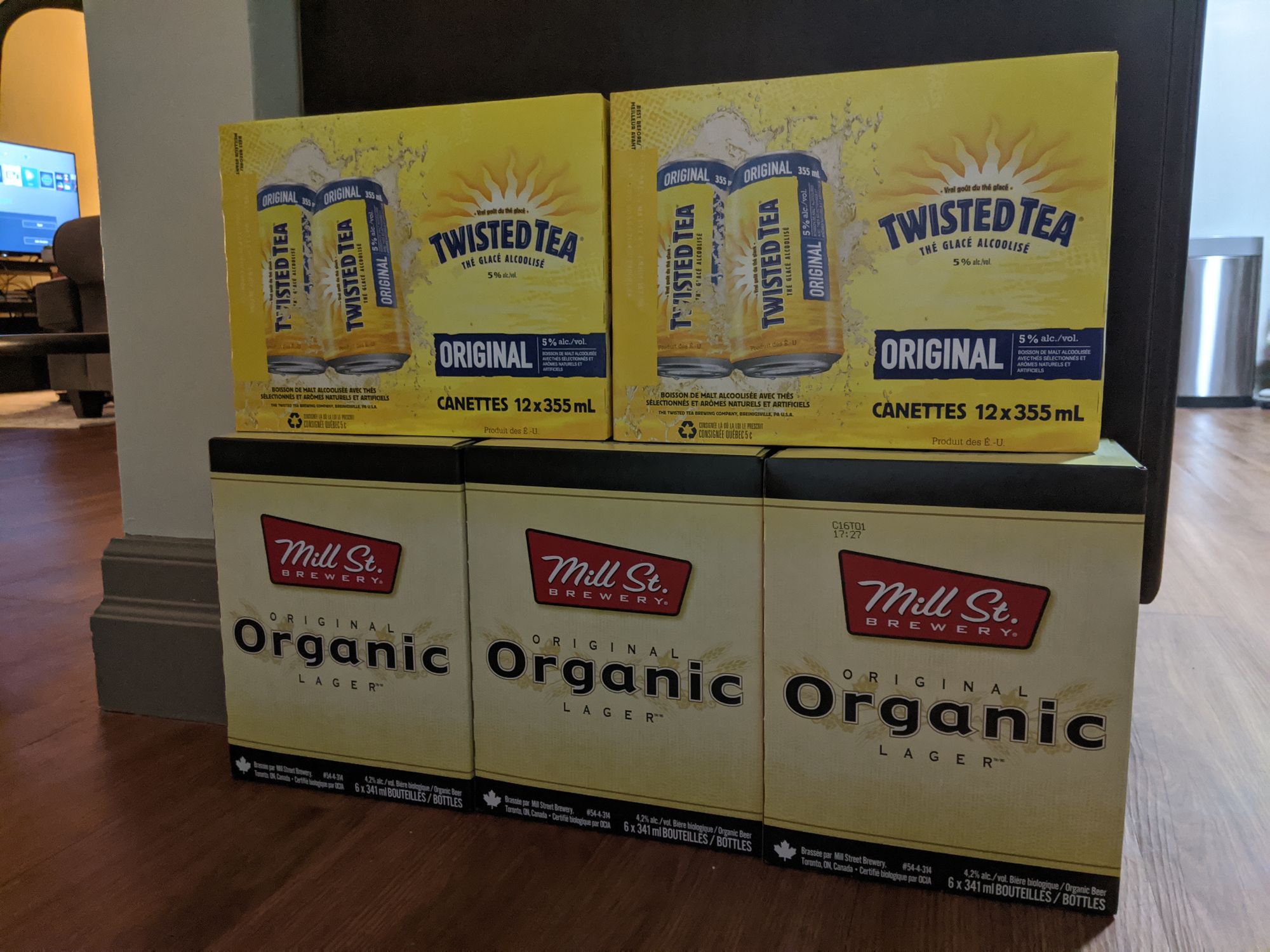 Boxes of alcohol on the floor. Twisted Teas stacked on top of multiple boxes of Mill St. Organic beer