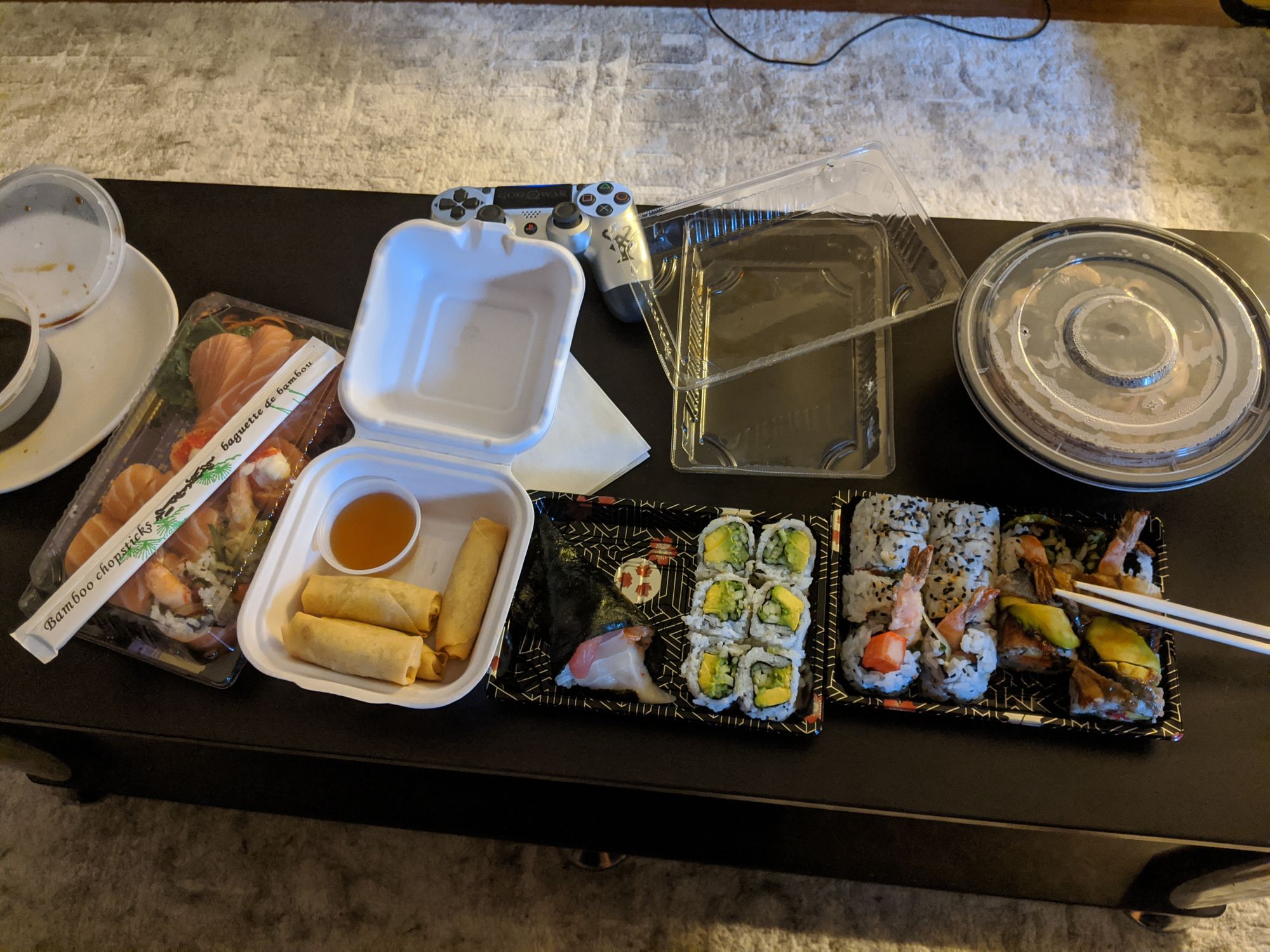 A top down image of take out sushi on our black coffee table.