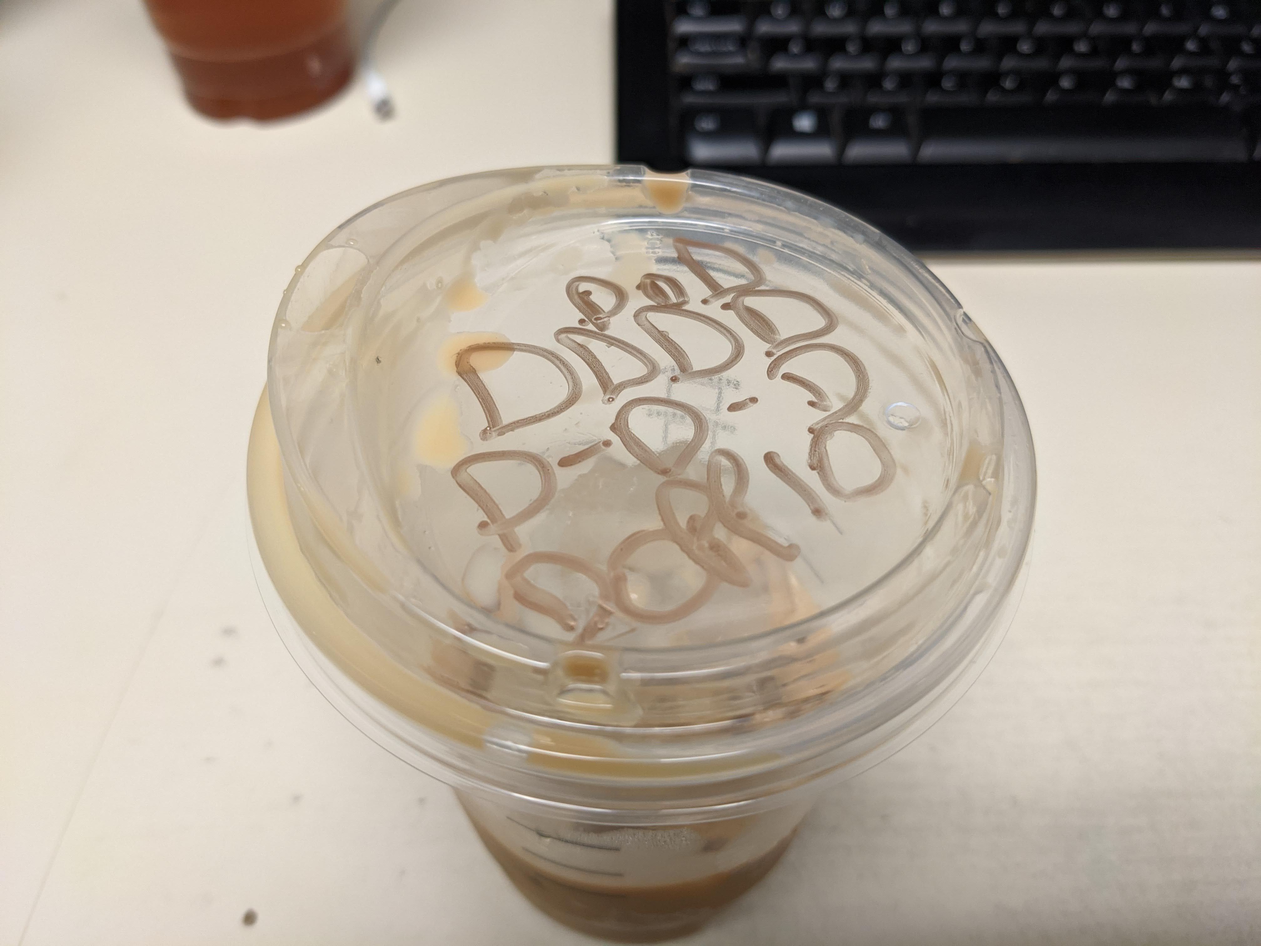 The top of a plastic iced cup that says D D D D D D DOPPIO
