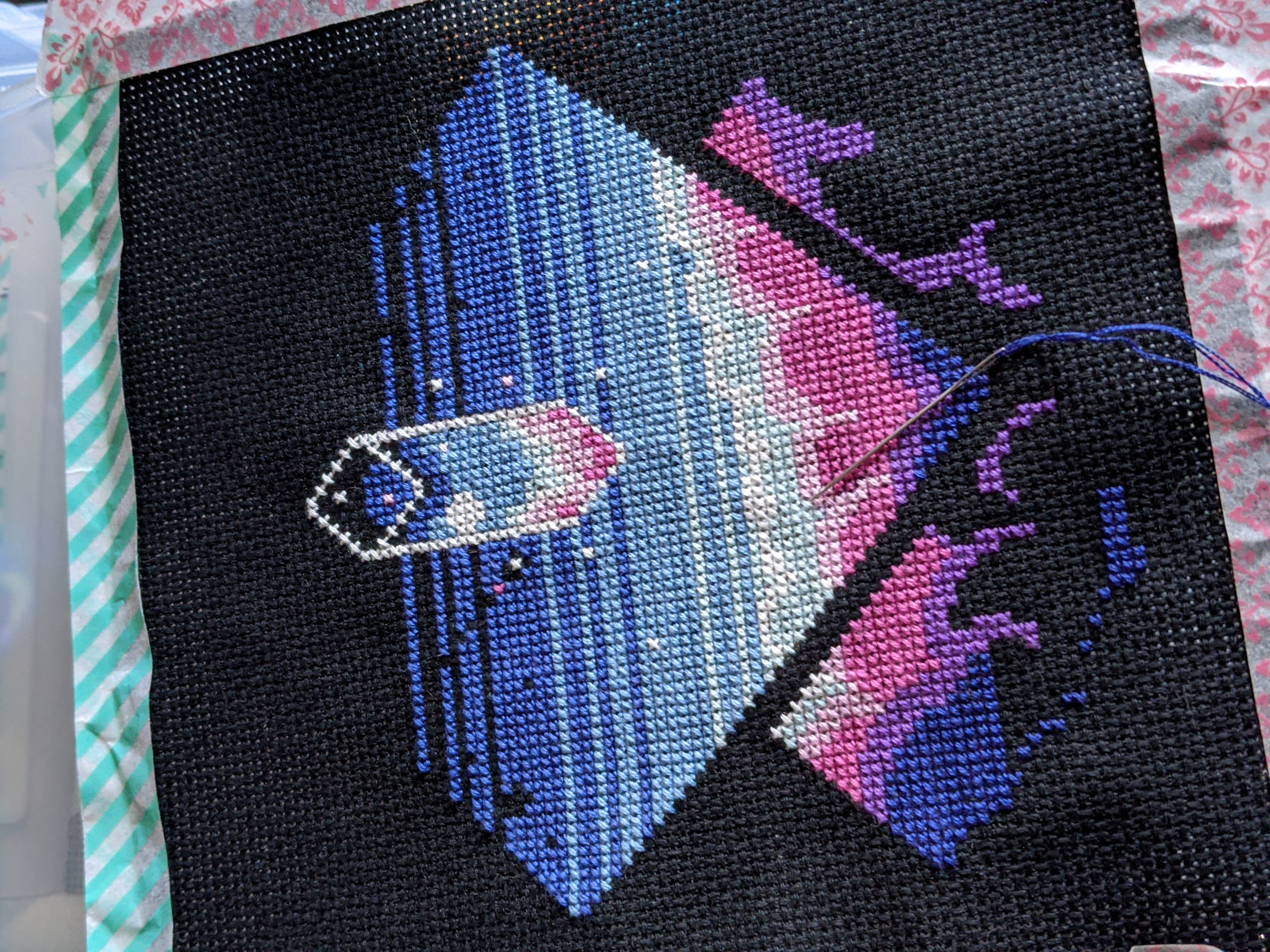 An abstract pixel art piece being turned into a cross stitch piece. It's a variety of blues, purples, pinks, and white.