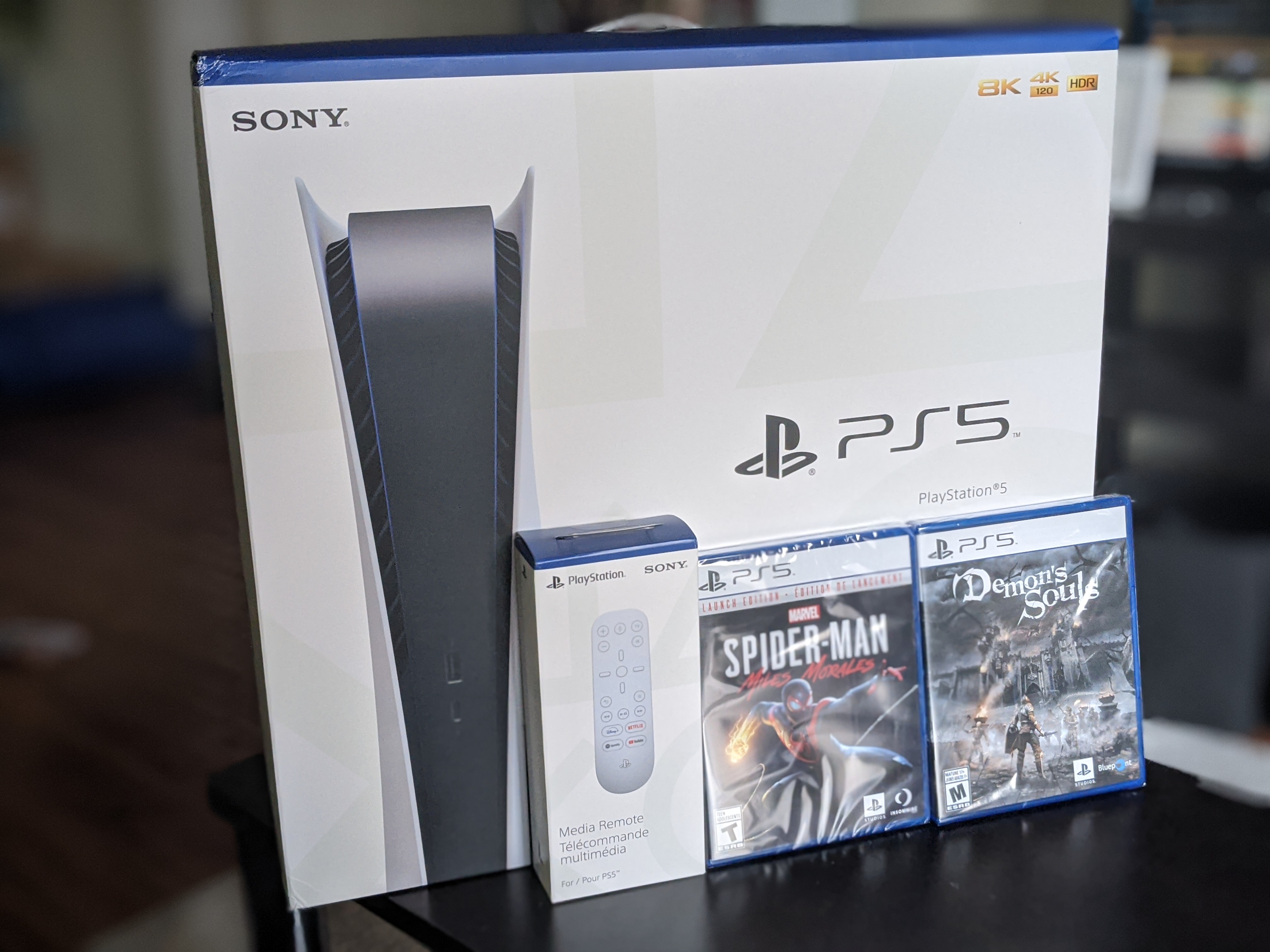 A PS5 box with the Media Remote, Spider-man Miles Morales, and Demon's Souls positioned in front of it.
