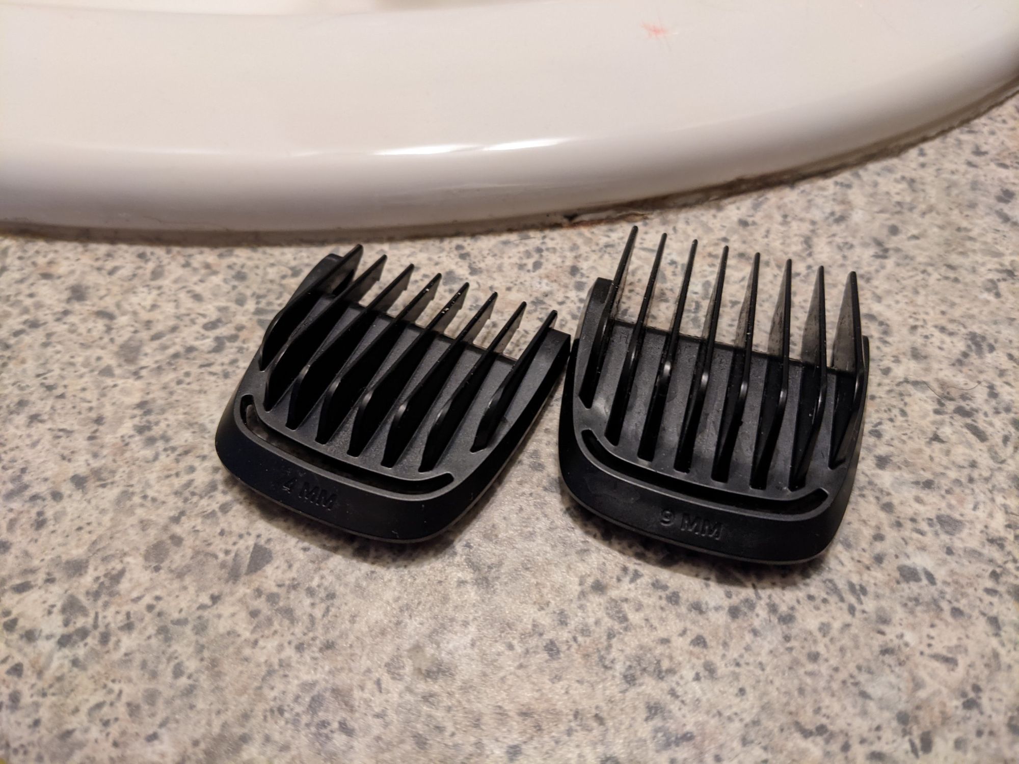  Two black clipper guards sitting on a bathroom counter. 